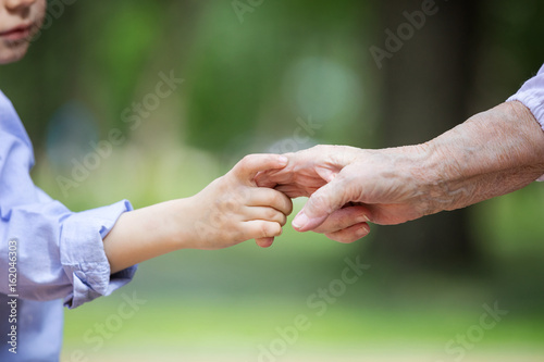 Young boy holding great grandmother's hand