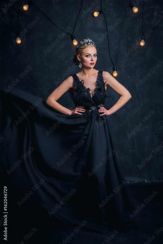 Fototapeta premium Beautiful woman in crown on dark background