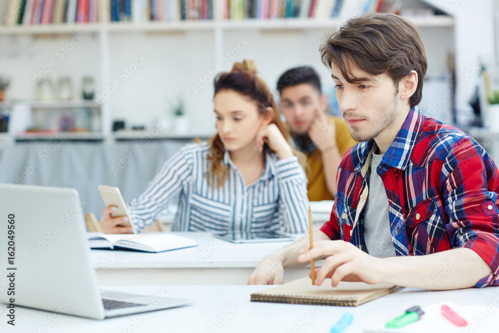 Serious student reading online data or carrying out test at lesson Serious student reading online data or carrying out test at lesson