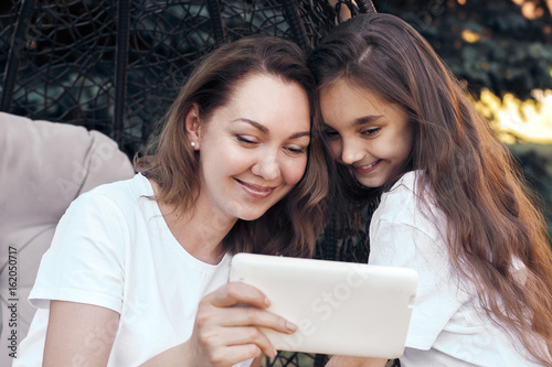 Happy mother and daughter using white tablet PC,