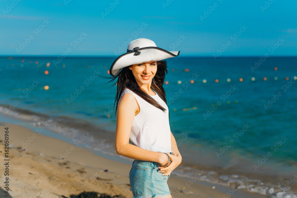 Brunette in a hat on the background of the sea