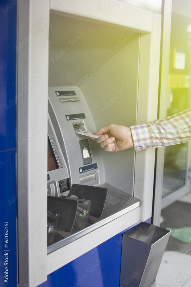 Hand of a man with a credit card, using an ATM. Man using an atm machine with his credit card. Closeup of male hands using smart phone while typing on ATM.
Hand of a man with a credit card, using an ATM. Man using an atm machine with his credit card. Closeup of male hands using smart phone while typing on ATM.