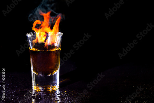 Hot alcoholic cocktail burning in shot glass. photo