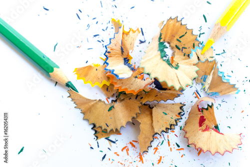 Wooden colorful pencils with sharpening shavings, on white paper