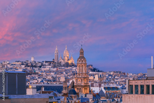 Aerial view of Sacre-Coeur Basilica or Basilica of the Sacred Heart of Jesus at the butte Montmartre and Saint Trinity church at nice sunset, Paris, France © Kavalenkava