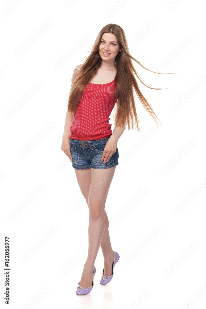 Naklejka premium Full length of smiling leggy young female in denim shorts and red top with beautiful long hair, isolated on white background