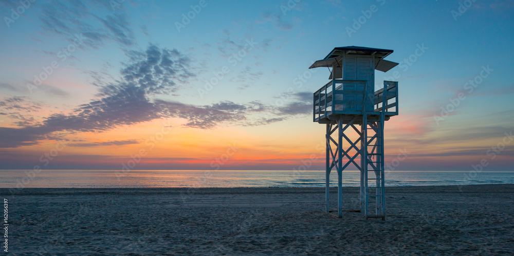 Obraz premium Sunrise over sea and sandy beach in spring