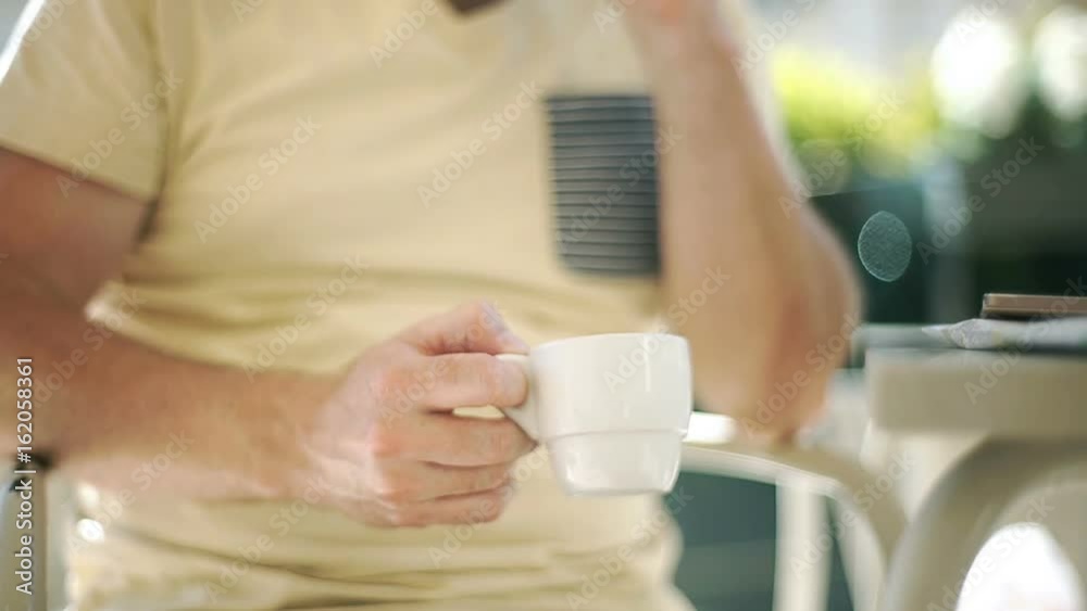 Man holding coffee and talking on cellphone in the cafe
Man holding coffee and talking on cellphone in the cafe