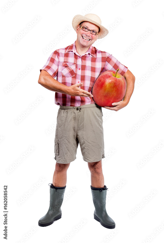 Gardener offers large red apple isolated on white background. Cheerful farmer shows harvest fruits. Funny man carries a big fresh apple.Genetically modified food. Gardener offers large red apple isolated on white background. Cheerful farmer shows harvest fruits. Funny man carries a big fresh apple.Genetically modified food.