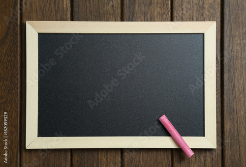 empty blackboard with chalks on vintage wooden background