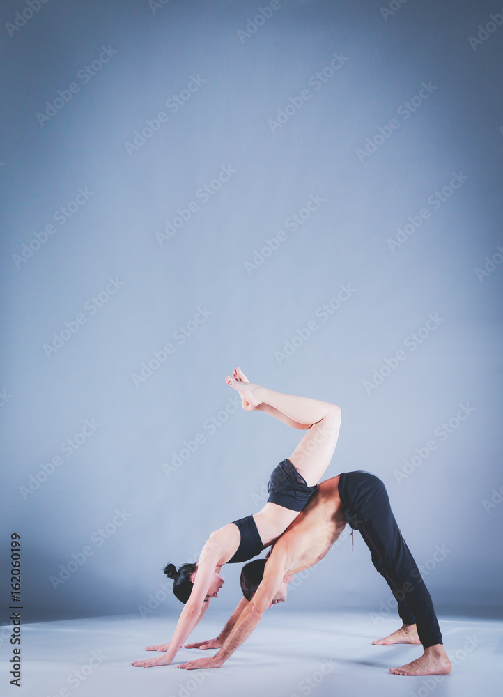 Young couple practicing acro yoga on mat in studio together. Acroyoga. Couple yoga. Partner yoga. Young couple practicing acro yoga on mat in studio together. Acroyoga. Couple yoga. Partner yoga.