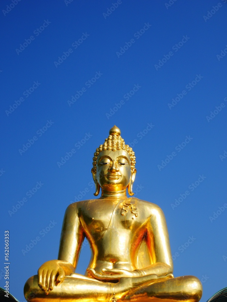 Golden Buddha statue on bright blue sky Golden Buddha statue on bright blue sky