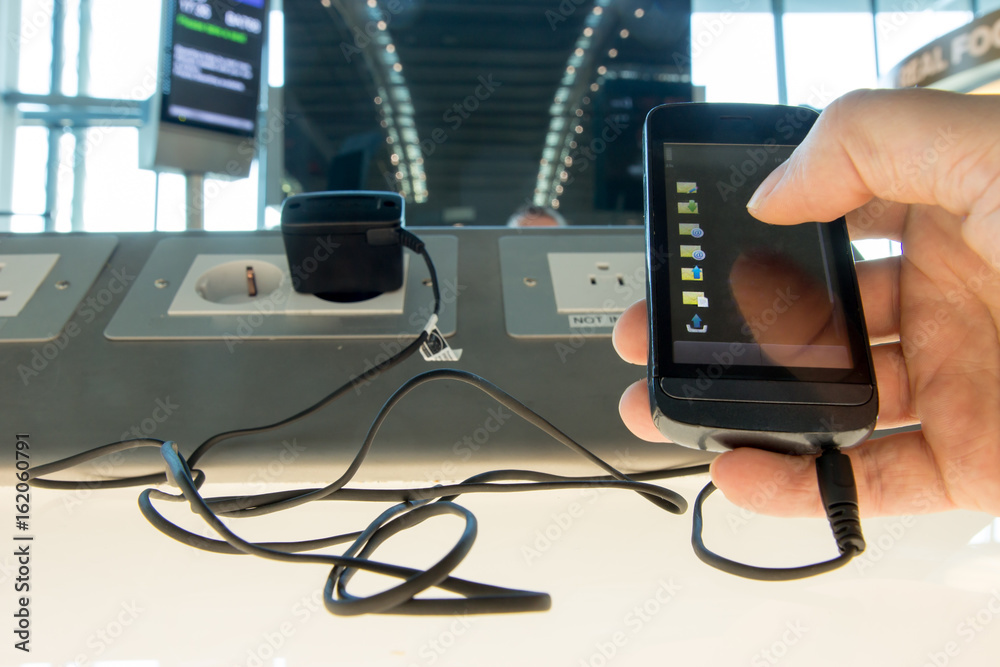 Using a mobile phone while charging the battery at the airport. Phone