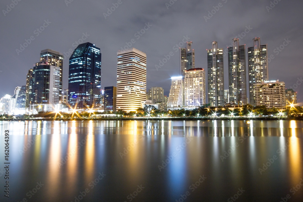 Office building edge lake in Bangkok city at night.