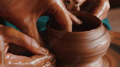 Creating a clay pot.Gonchar.Potter.A turner.Workshop of clay.Clay on the device.Master.Hands working on pottery wheel, shaping a clay pot photo