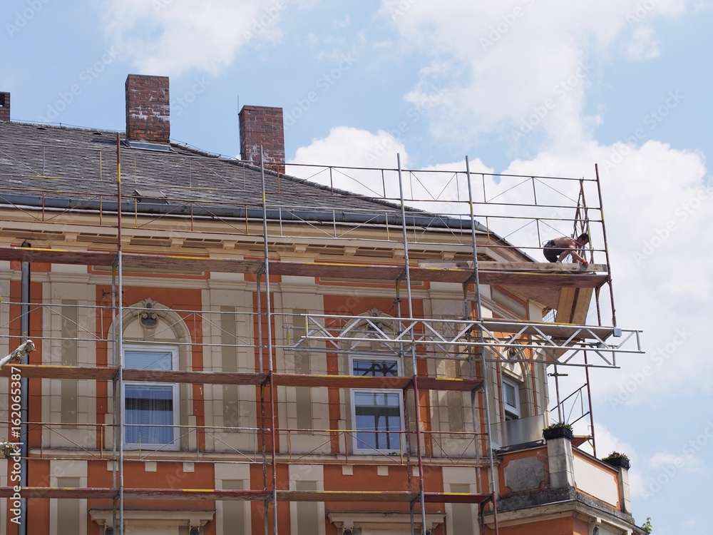 Fassadenbau - Handwerker arbeitet hoch oben auf einem Baustellengerüst Fassadenbau - Handwerker arbeitet hoch oben auf einem Baustellengerüst
