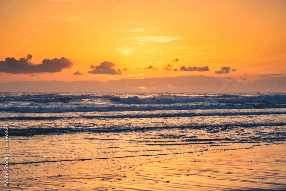 Obraz premium Ocean waves at the beach during sunset.