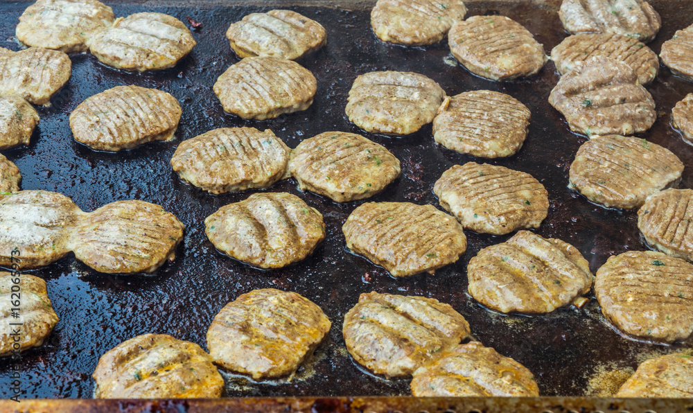 The meat is frying. Many pieces are fried in a restaurant in a large frying pan. The meat is frying. Many pieces are fried in a restaurant in a large frying pan.