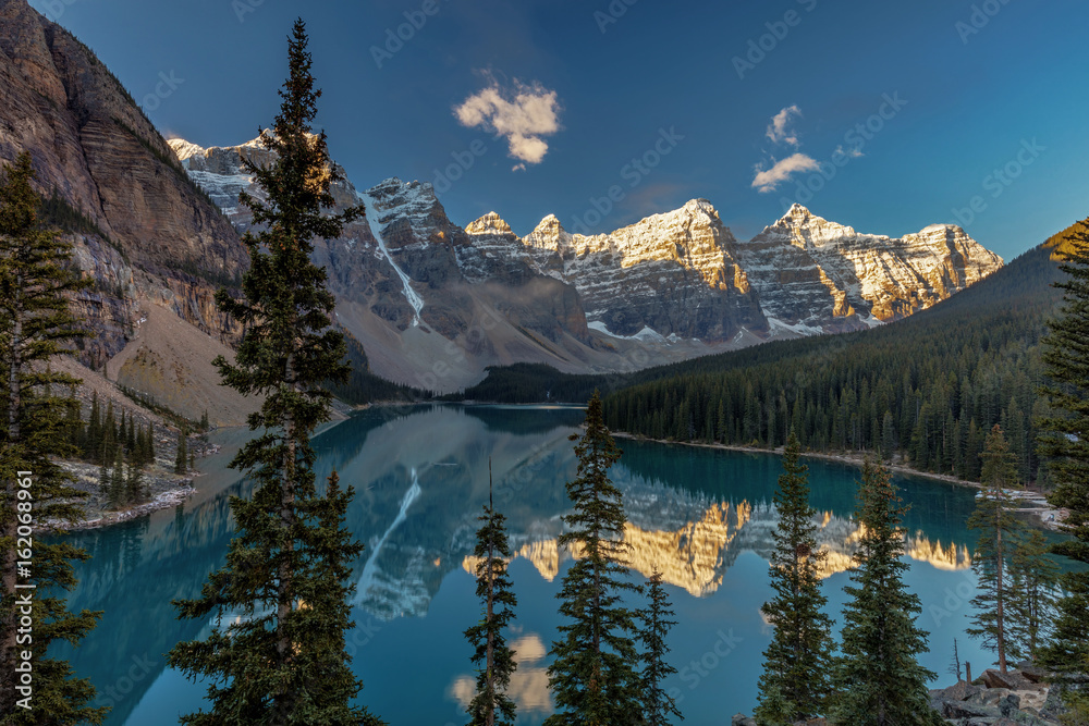 Majestic Moraine Lake in Banff National Park, Alberta. Stunning natural beauty, tall snow covered peaks, lush forest and wilderness and the jewel of the Canadian rocky mountains.