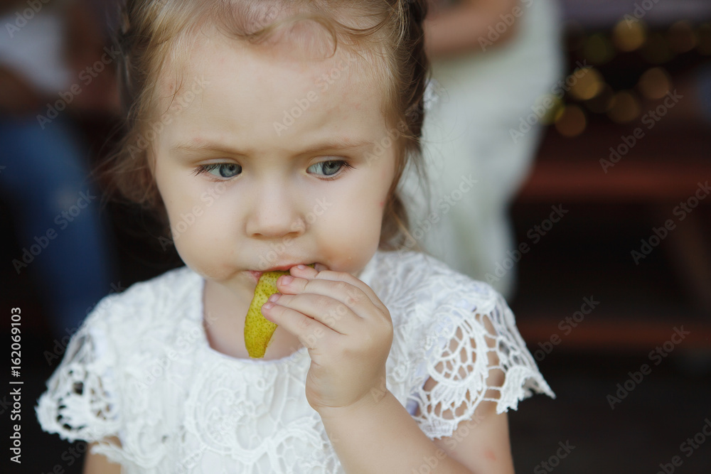 Little girl eating an Apple thoughtfully looking to the side Little girl eating an Apple thoughtfully looking to the side