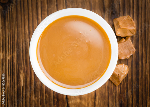 Portion of Caramel Sauce on wooden background (selective focus)