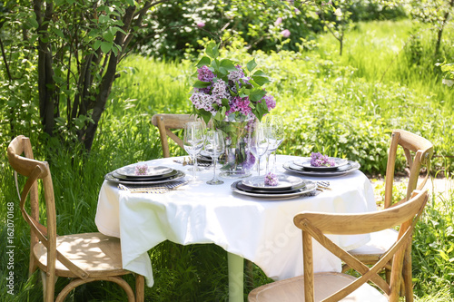Beautiful table setting with lilac flowers decoration outdoors