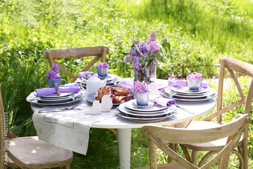 Beautiful table setting with lilac flowers decoration outdoors