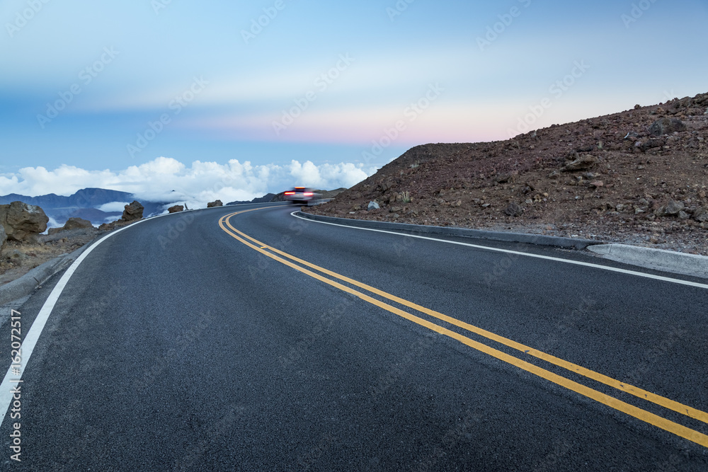 Naklejka premium Mountain road above the clouds after sunset