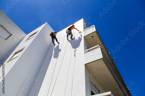 industrial alpinist work on white wall