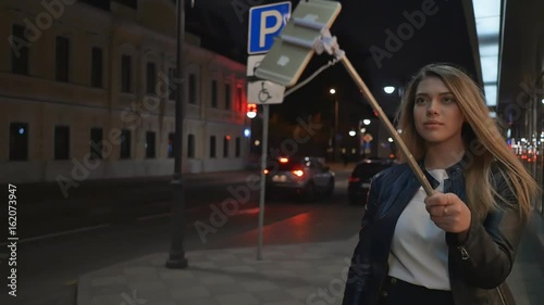 A young blonde girl makes a selfie photograph using a stick of stick. Live and create stories for social networks. photo