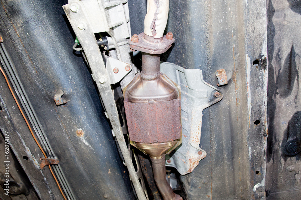 Underside of a car reveals an exhaust pipe with gasoline pipe lifted for maintenance