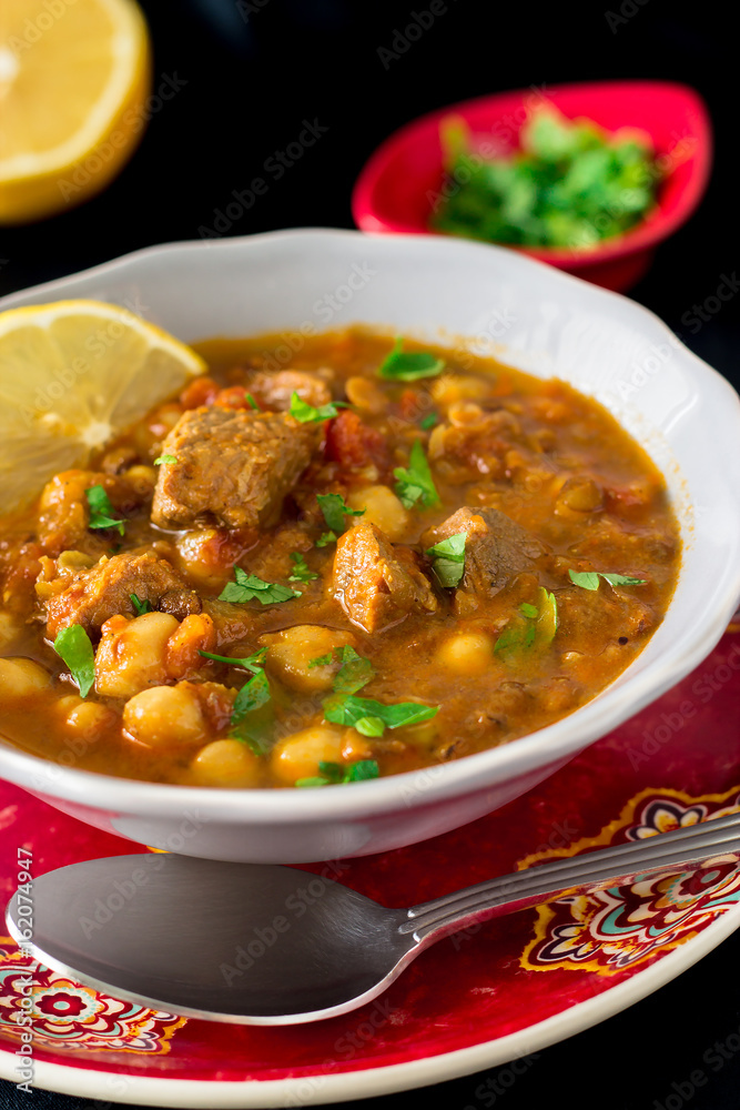 Famous Moroccan soup harir with meat, chickpeas, lentils, tomatoes and spices. Dark vertical photo