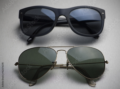 Close-up of two different types of sunglasses on gray background.