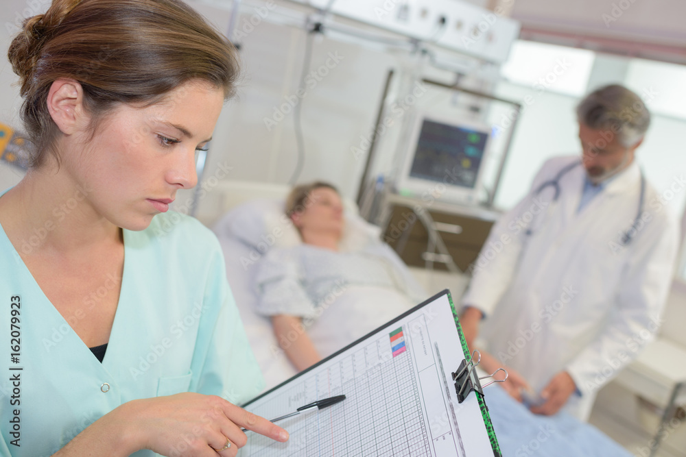 Fototapeta premium nurse with clipboard in her hands registering womans healthcare stats