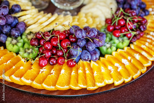 Fotografija A fruit dish with oranges, kiwi fruit, grapes, cherries and pineapples