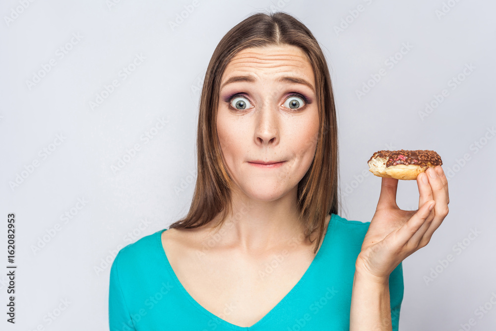 Portrait of beautiful girl with chocolate donuts. amazed and looking at camera with surprised big eyes. studio shot on light gray background. Portrait of beautiful girl with chocolate donuts. amazed and looking at camera with surprised big eyes. studio shot on light gray background.