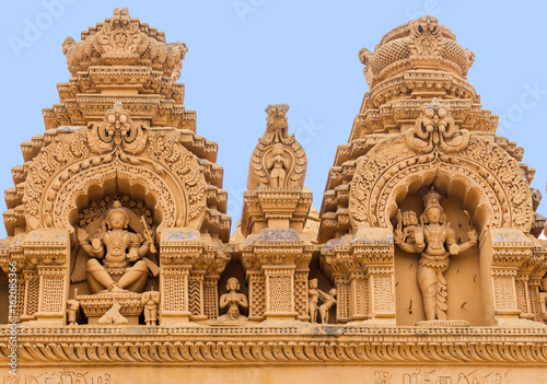 Nanjangud, India - October 26, 2013: Double Niche in beige elaborately decorated sandstone at Srikanteshwara Temple showing both statue of Lord Shiva. Sexual imagery nearby. photo
