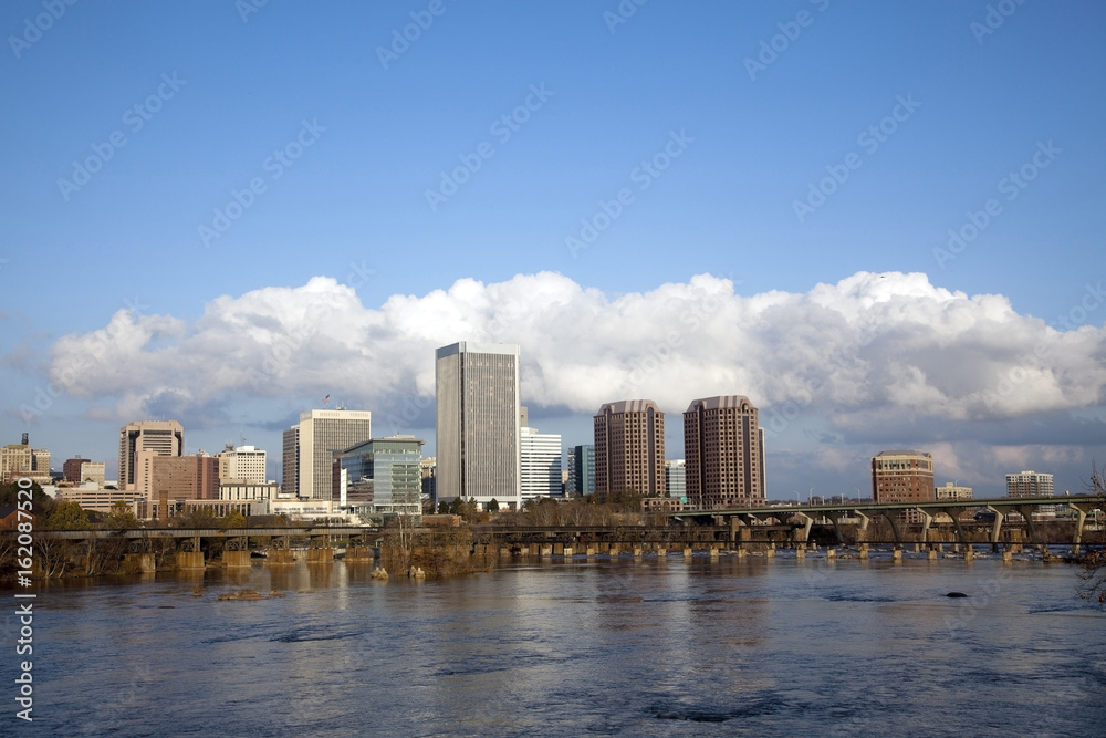 Richmond, Virginia cityscape skyline with blue sky and clouds on the James River.