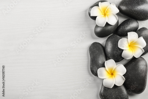 Spa stones with plumeria flowers on light background