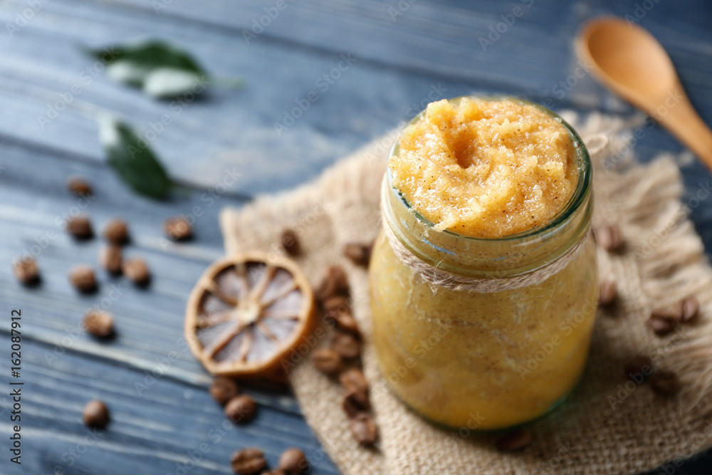 Glass jar with scrub, dried lemon slice and coffee grains on wooden background Glass jar with scrub, dried lemon slice and coffee grains on wooden background