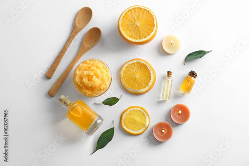Wooden spoons, bowl with scrub, bottles of oil, candles and orange slices isolated on white