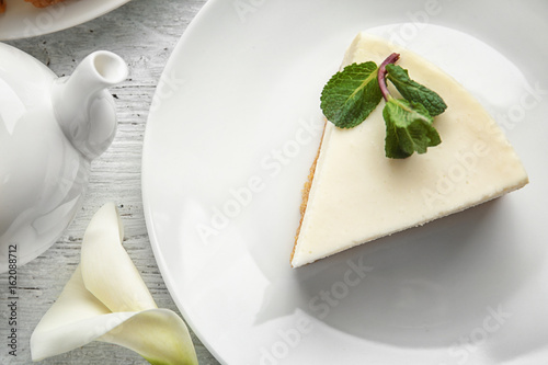 Plate with piece of delicious cheesecake on table