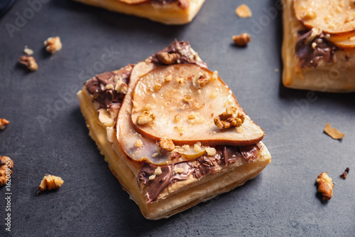 Delicious pastry with chocolate, pear and nuts on grey background