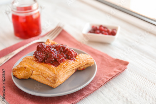 Tasty puff pastry with cherry on plate