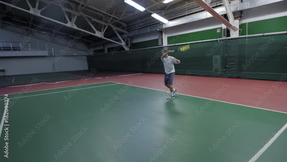 An adult man plays tennis, an athlete beats the ball through the net with a racket, he plays with a partner on the court An adult man plays tennis, an athlete beats the ball through the net with a racket, he plays with a partner on the court