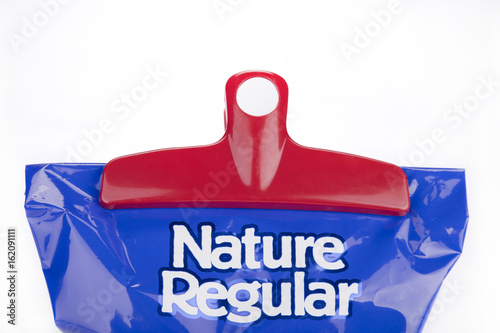 Red plastic chips bag clip on a blue bag of chips. Bag clip and chips bag isolated on white background.