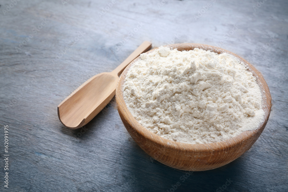 Bowl with flour and scoop on wooden background Bowl with flour and scoop on wooden background