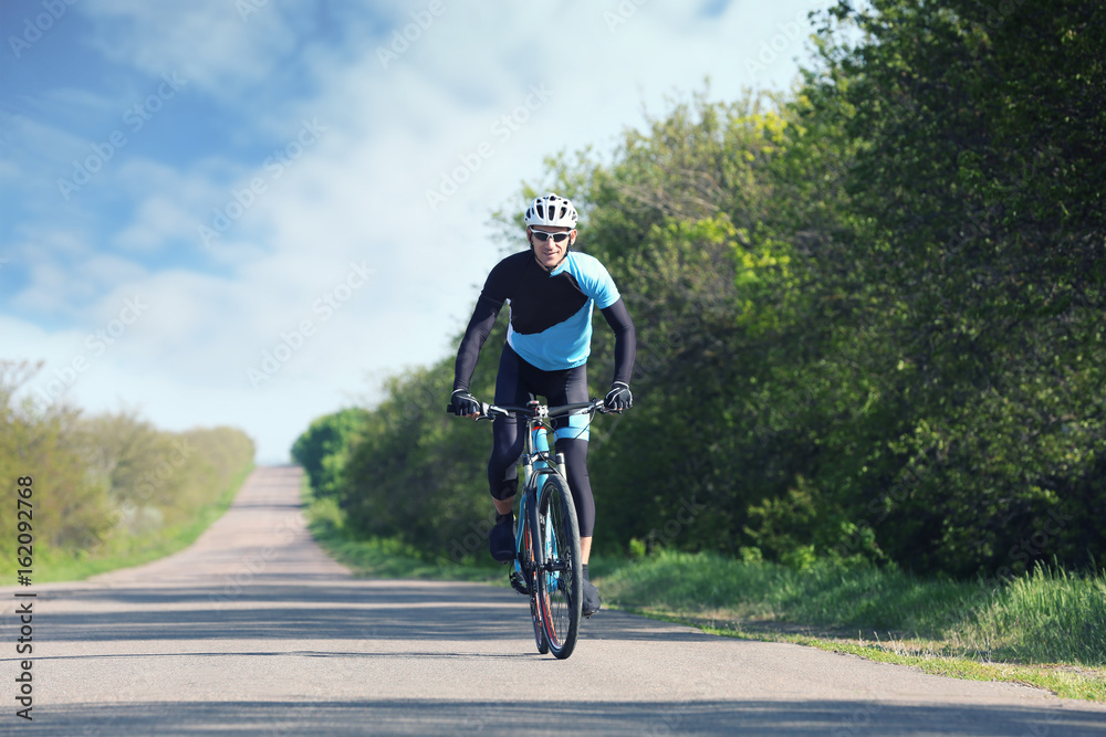Sporty cyclist riding bicycle outdoors on sunny day Sporty cyclist riding bicycle outdoors on sunny day