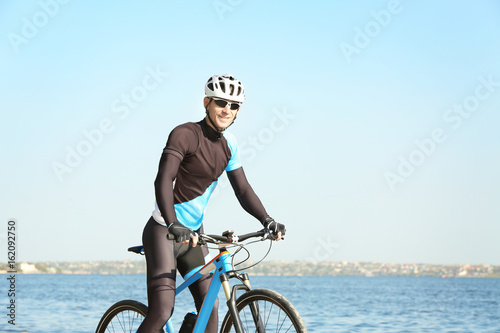 Sporty cyclist riding bicycle near river