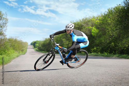 Fototapeta Naklejka Na Ścianę i Meble -  Sporty cyclist riding bicycle outdoors on sunny day